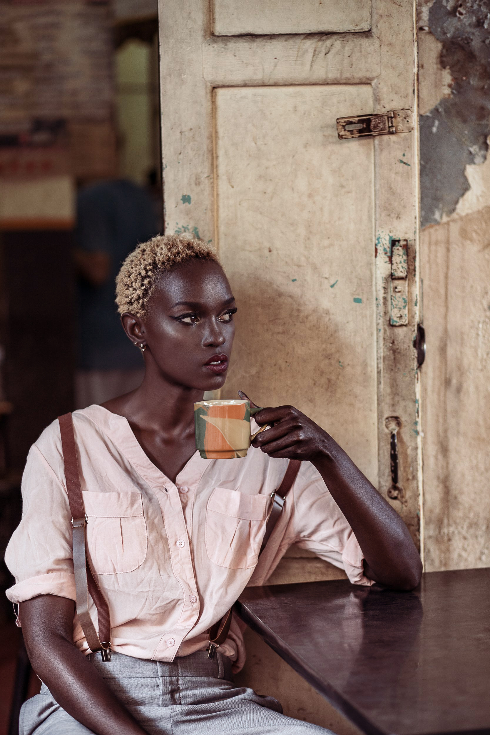 Portrait of a woman at a wooden table holding a patterned ceramic cup